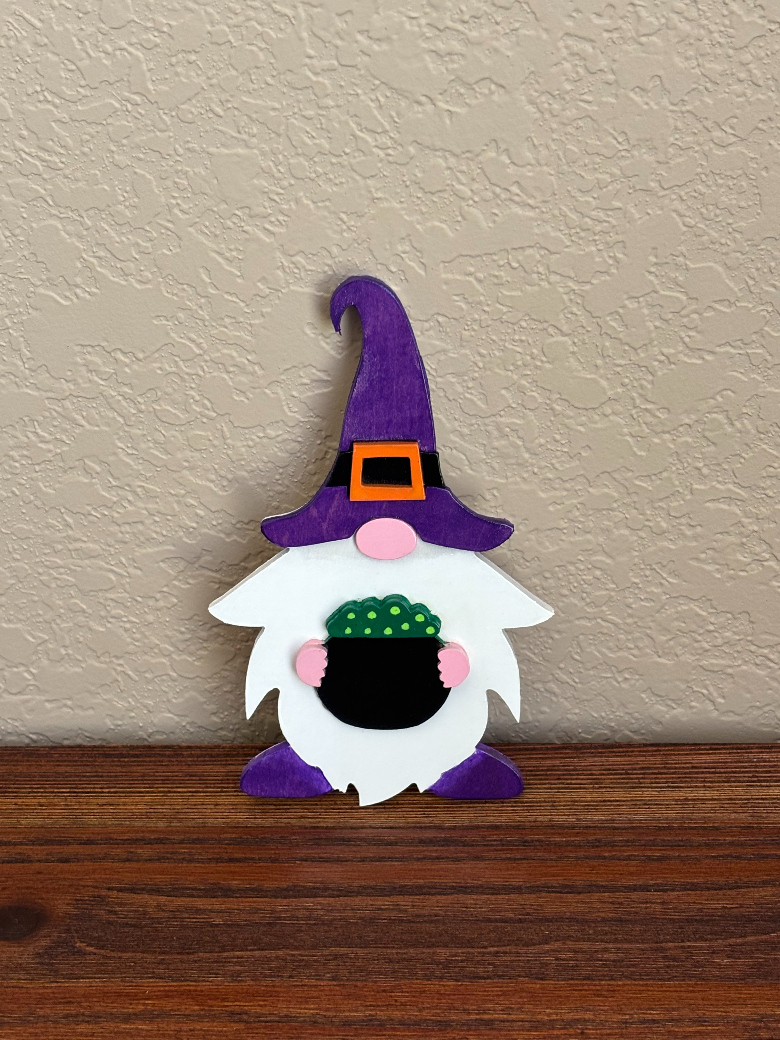Halloween-themed gnome figurine with a purple hat on a wooden surface.