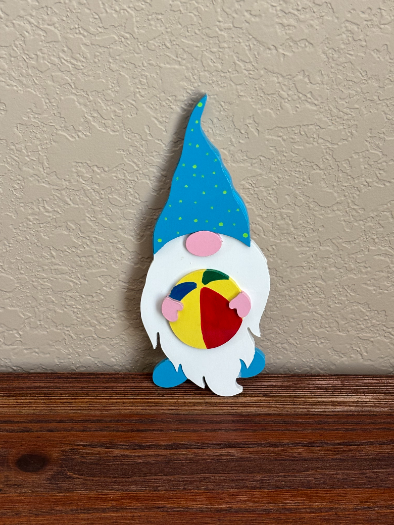 Colorful gnome figurine with a blue hat on a wooden surface against a beige wall.